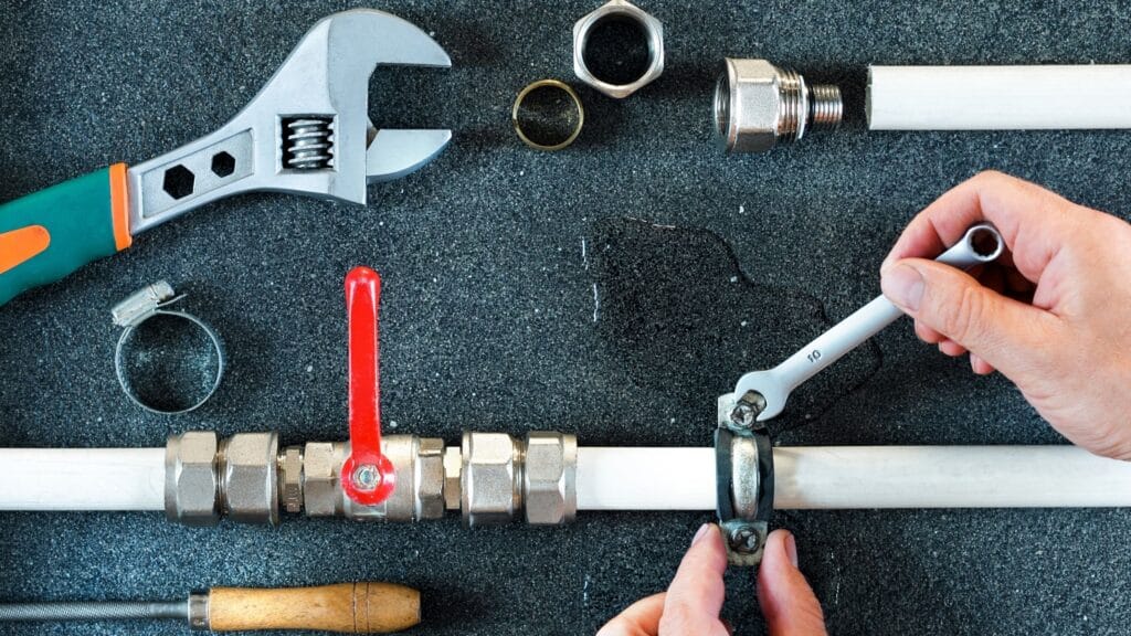 Plumber repairing a pipe valve with an adjustable wrench in North Port