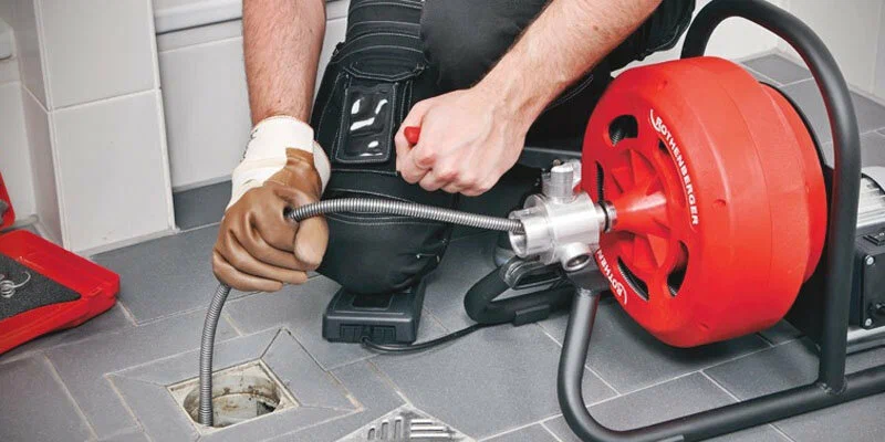Plumber using a drain-cleaning machine in North Port