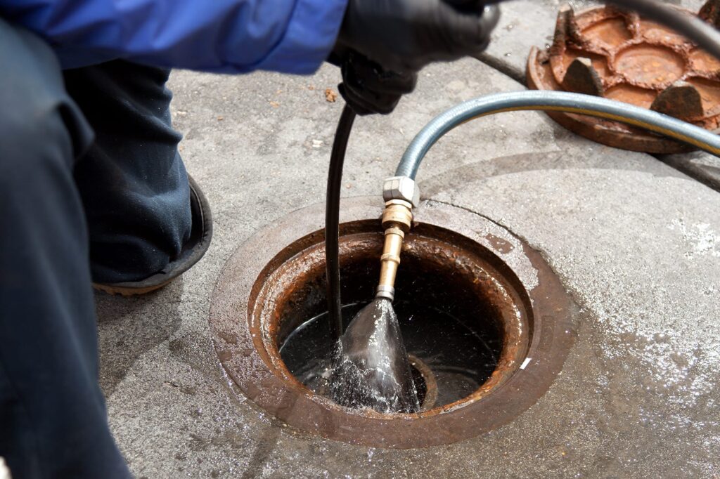 Plumber hydro jetting a sewer line through a manhole in North Port