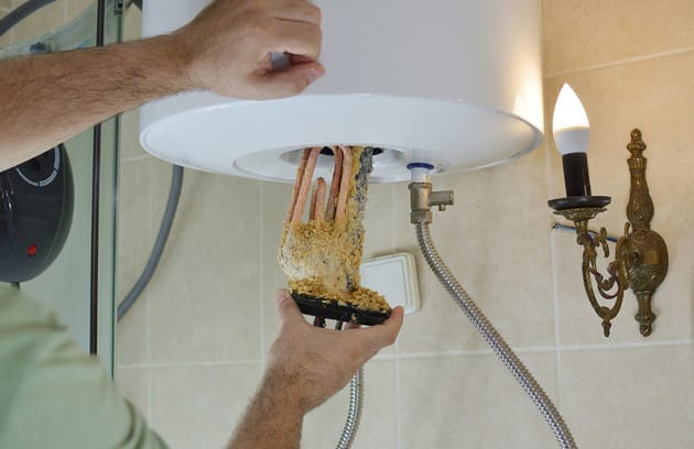 Technician removing mineral buildup from a water heater in North Port